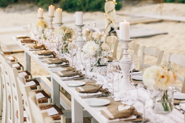 Long dinner table decorated with flaxen cloth and white candles