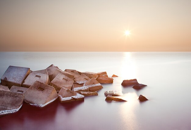 A long exposure of rock formations in the sea at sunset