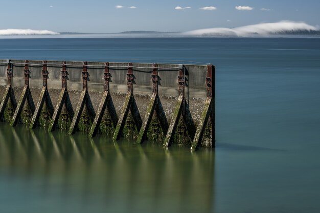 Long exposure waterscape scene of an old weathered sea wall surrounded by soft seawater