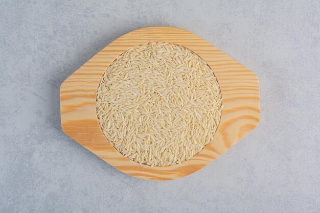 Long grain rice piled on a wooden plate on marble surface