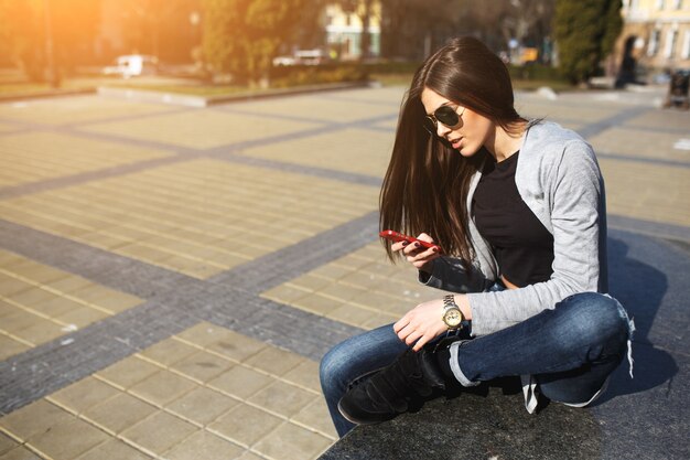 Long-haired girl using her mobile in the square