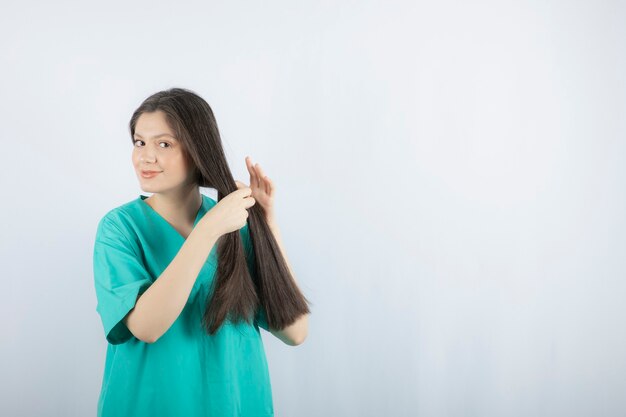 Длинноволосая медсестра плетет ей волосы.