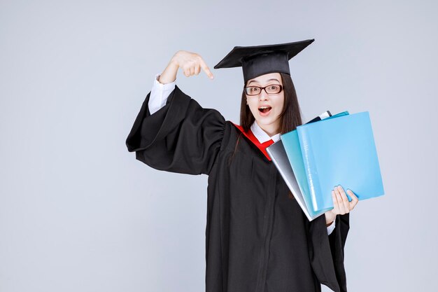 Long haired student in glasses folders in her hand standing. High quality photo