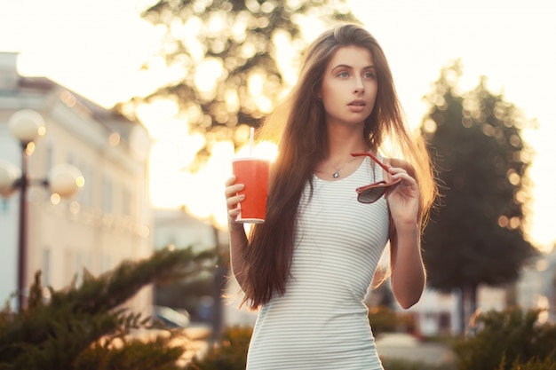 Foto gratuita adolescente dai capelli lunghi in possesso di un soda e occhiali da sole