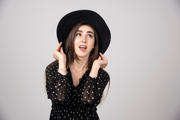 Long haired woman in black dress looking at camera with surprised expression.