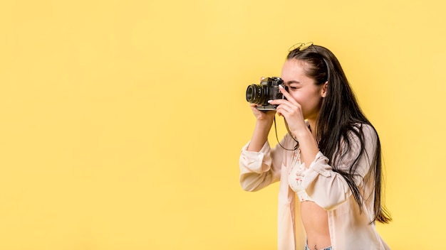 Long haired woman holding photo camera and taking picture