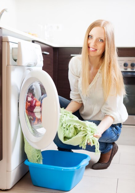 long-haired woman loading clothes into the washing machine