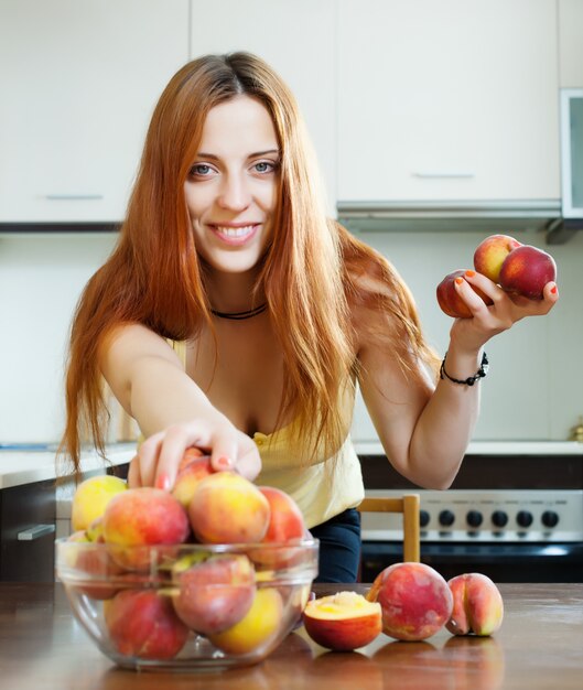 long-haired woman taking peaches at table