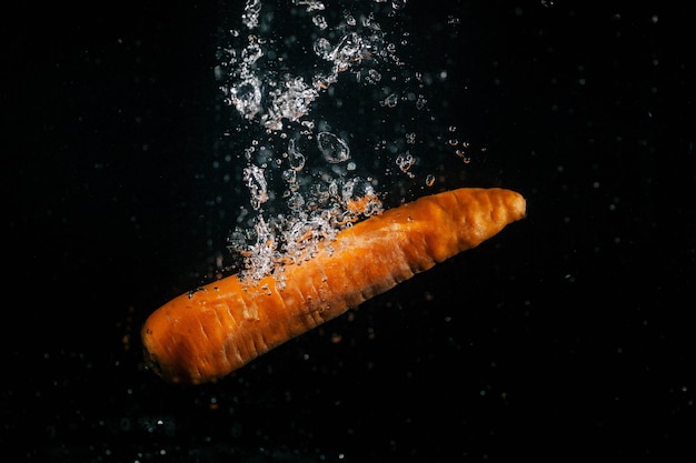 La carota arancione lunga cade in acqua