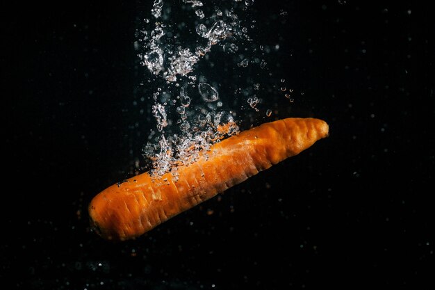 長いオレンジ色のニンジンが水に落ちる