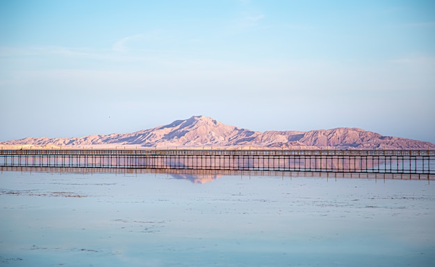 Free photo long pier among the sea and mountains. the sky is reflected in the water.