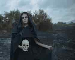 Free photo long portrait of a man dressed as dark witch with skull