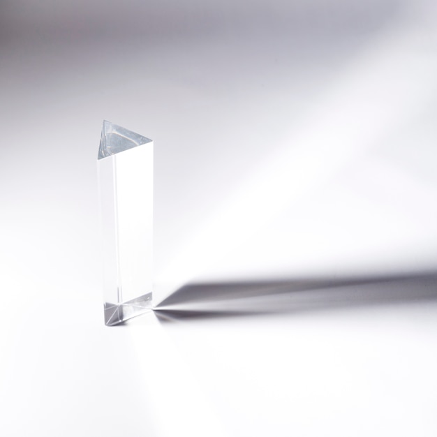 Long prism crystal with dark shadow on white backdrop