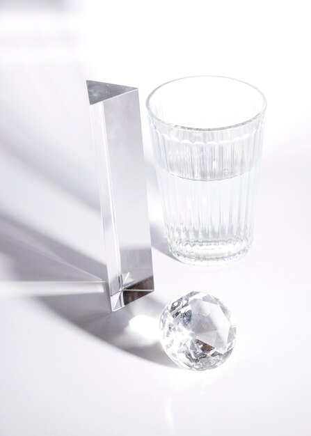 Long prism; diamond and glass of water in sunlight with shadow on white background