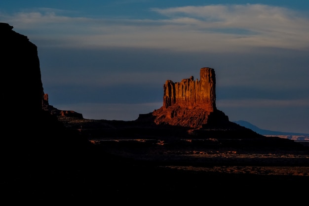 曇り空を背景に丘の上の大きな砂漠の岩のロングショット