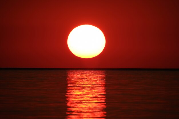 Long range shot of  sea reflecting the sun with the red sky