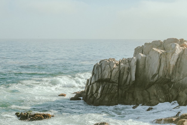 Long-range shot of sea waves hitting the cliff