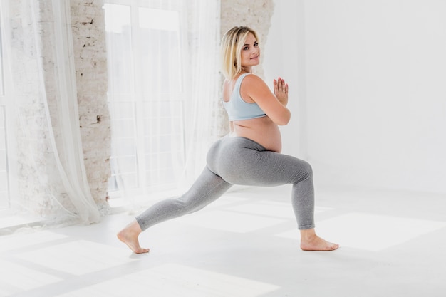 Free photo long shot beautiful pregnant woman exercising