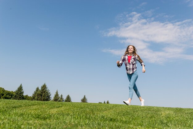 Long shot blonde girl running on grass