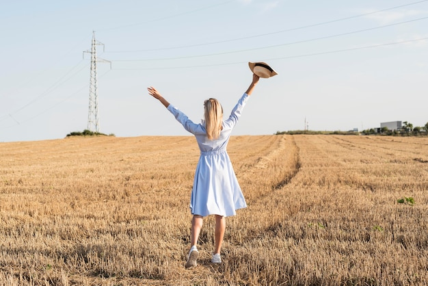 Donna bionda del colpo lungo che gode della natura in un campo