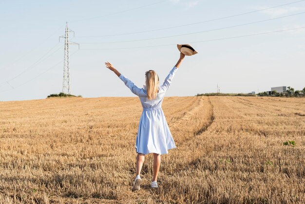 Long shot blonde woman enjoying the nature in a field