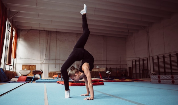 Long shot blonde woman training for gymnastics championship