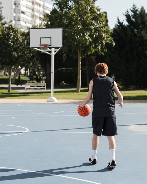 Foto gratuita colpo lungo del ragazzo che gioca a basket