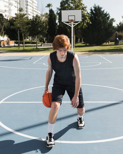 Free photo long shot of boy playing basketball