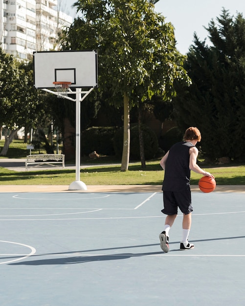 Long shot of boy playing basketball