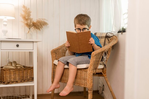 Long shot boy reading in an armchair