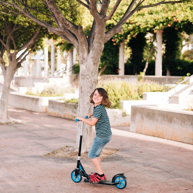 Long shot of boy with scooter in park