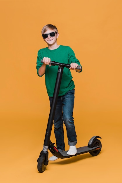 Длинный выстрел мальчика с очками на скутере