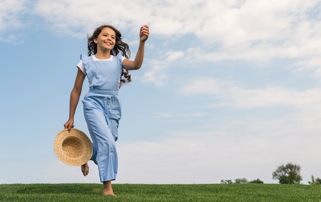 Long shot cheerful little girl running on grass