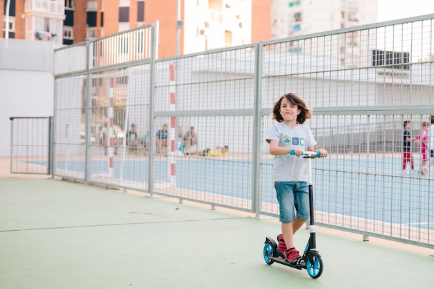 Foto gratuita colpo lungo del bambino sullo scooter