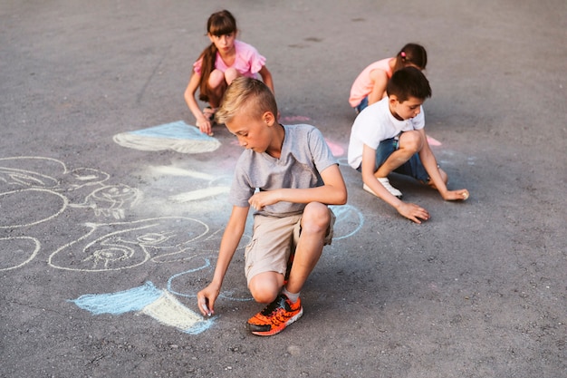 Bambini della possibilità remota che fanno disegno con il gesso