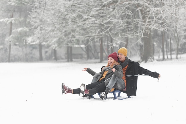 Long shot of couple being happy and sitting on the sleigh