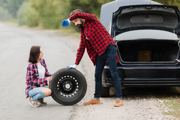 Long shot of couple changing tire