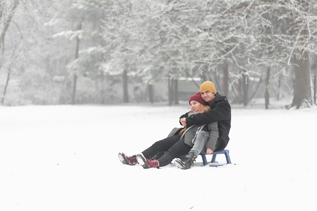 Free photo long shot of couple hugging and sitting on the sleigh