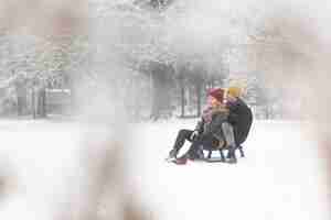 Free photo long shot of couple sitting on sleigh