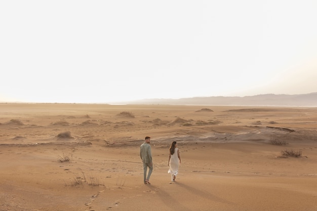 Long shot couple walking in desert