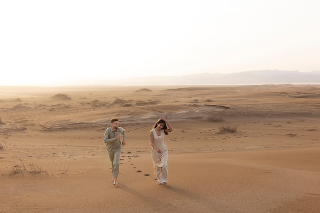 사막에서 걷는 긴 샷 귀여운 커플