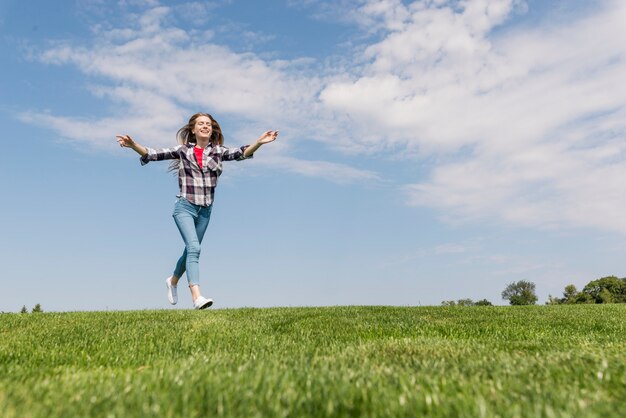 Long shot cute girl running on grass