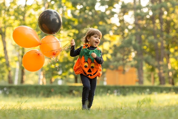 Colpo lungo del ragazzino sveglio in costume da zucca