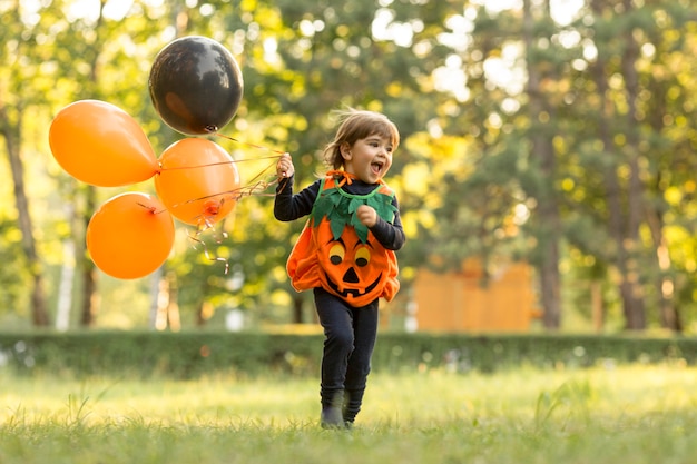 Long shot of cute little boy in pumpkin costume