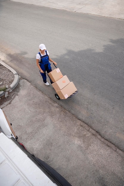 Long shot delivery woman carrying boxes