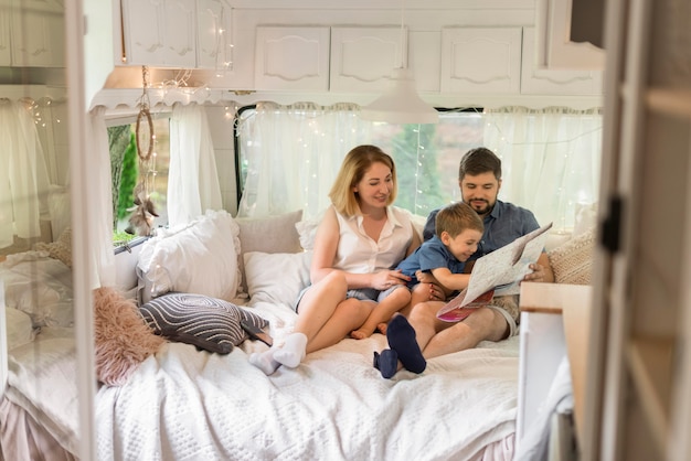 Long shot family looking through a map in a caravan