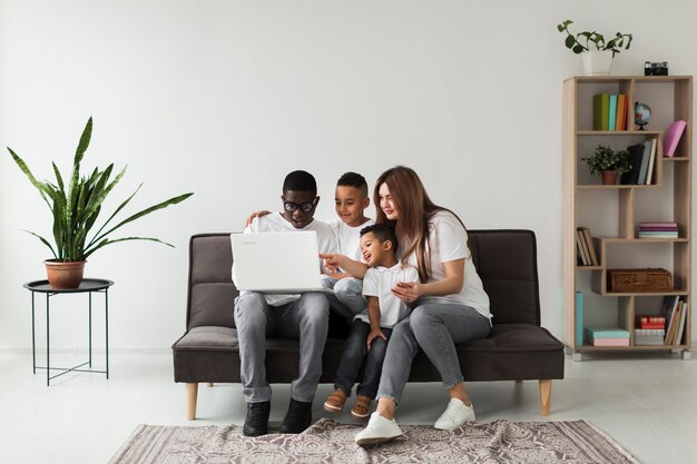 Long shot family looking together on a laptop