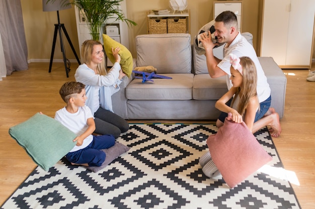 Long shot family playing with pillows