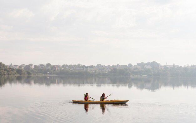 Long shot females rowing in kayak