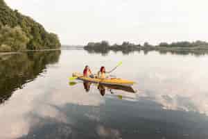 Free photo long shot girls rowing in kayak
